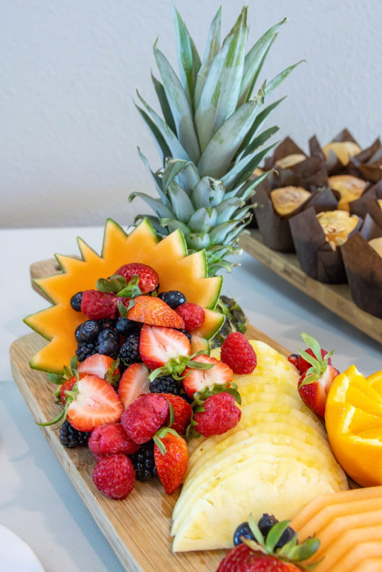 Photo of strawberries, oranges and blueberries pouring out of cut pineapple bowl