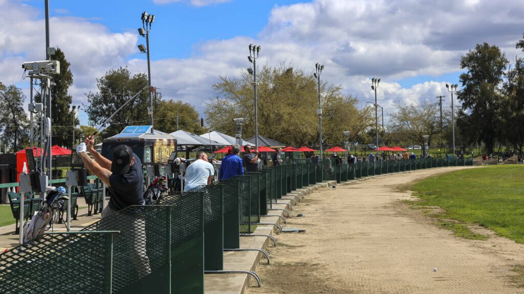 a wide shot of multiple golfers in their bay at the Haggin Oaks Driving Range