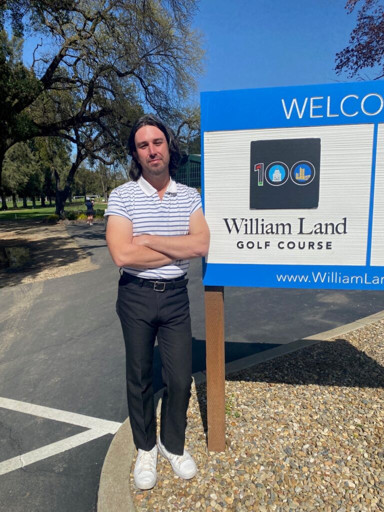 Photo of Chris Vogel in front of the William Land Golf Course Sign