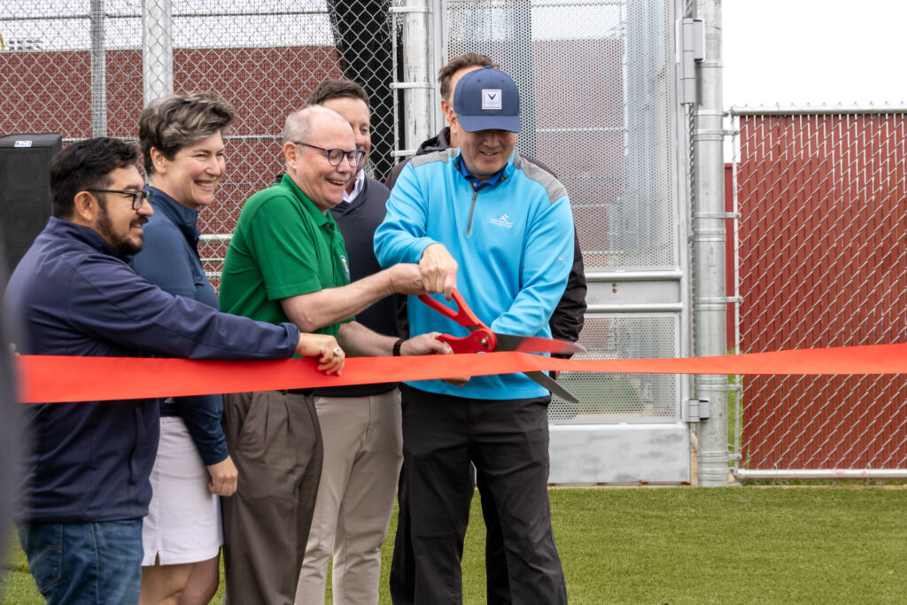 City council members and Angie Dixon from First Tee Greater Sacramento are holding the ceremonial ribbon while Rob Fong is preparing to cut the ribbon with scissors.