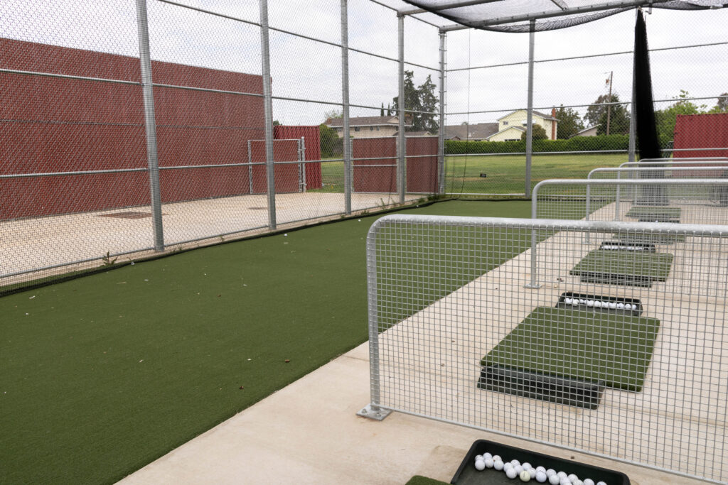Inside the encaged swing area at Hiram Johnson. It is a large fenced cage with a black net around the inside. There are 5 bays that students will be able to swing from.