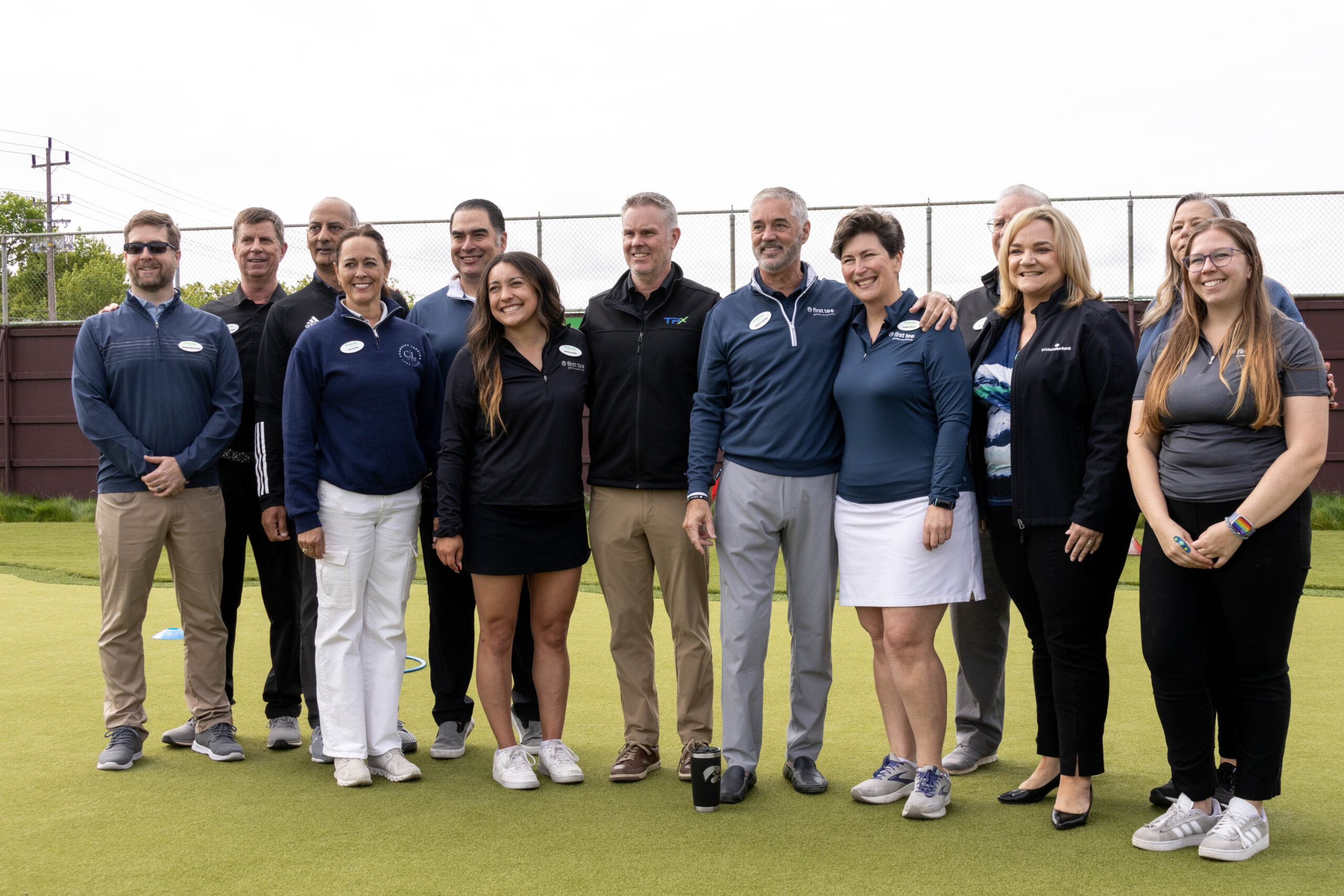 A group photo of everyone from the First Tee Greater Sacramento at the ribbon cutting ceremony. They are standing on the practice green of the golf facility.