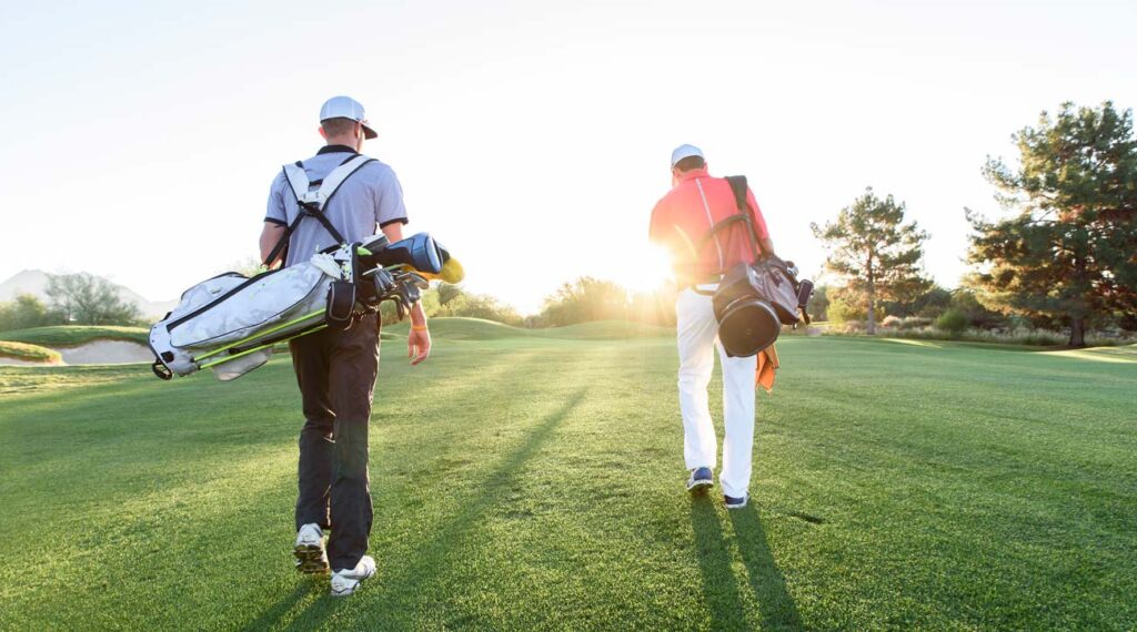 Two Golfers walking on golf course with sun setting
