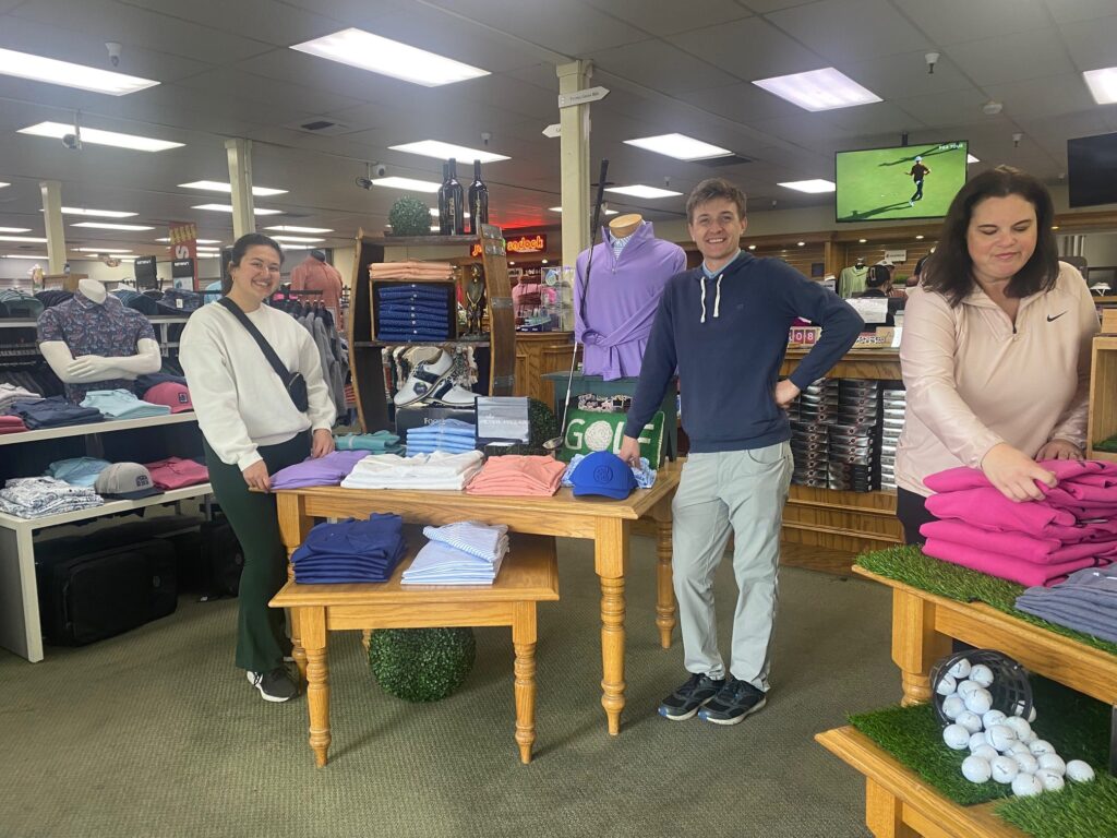 Three people standing in front of clothing rack
