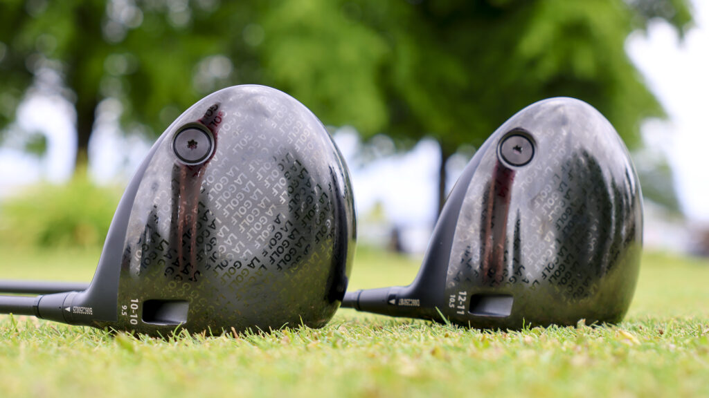 Two LA Golf drivers are lined up and laying on the ground.