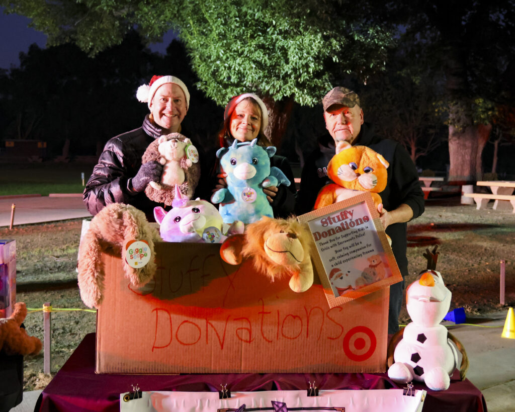 Kristina and other LPCA members hold toys while standing behind the full Sheriff's Toy Project donation box.