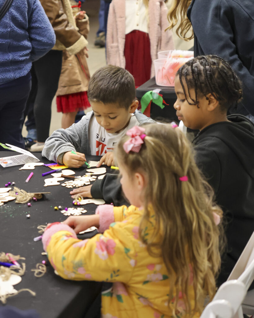 A table of children decorating and coloring their own holiday ornaments to take home.