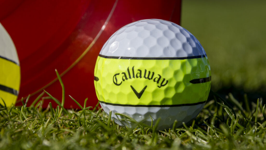 A closeup of a Callaway Chrome Soft ball with a bright yellow alignment aid.