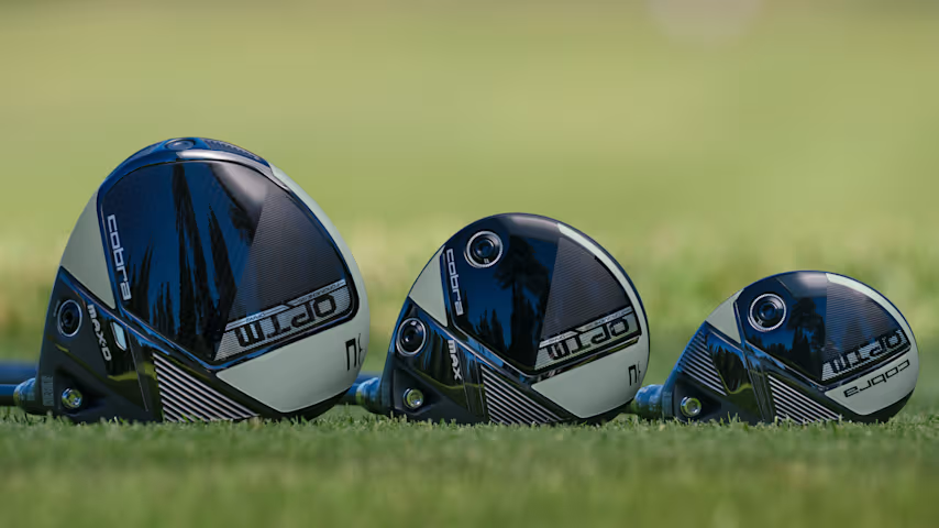 A Cobra OPTM driver, fairway wood, and hybrid lined up next to each other on grass.