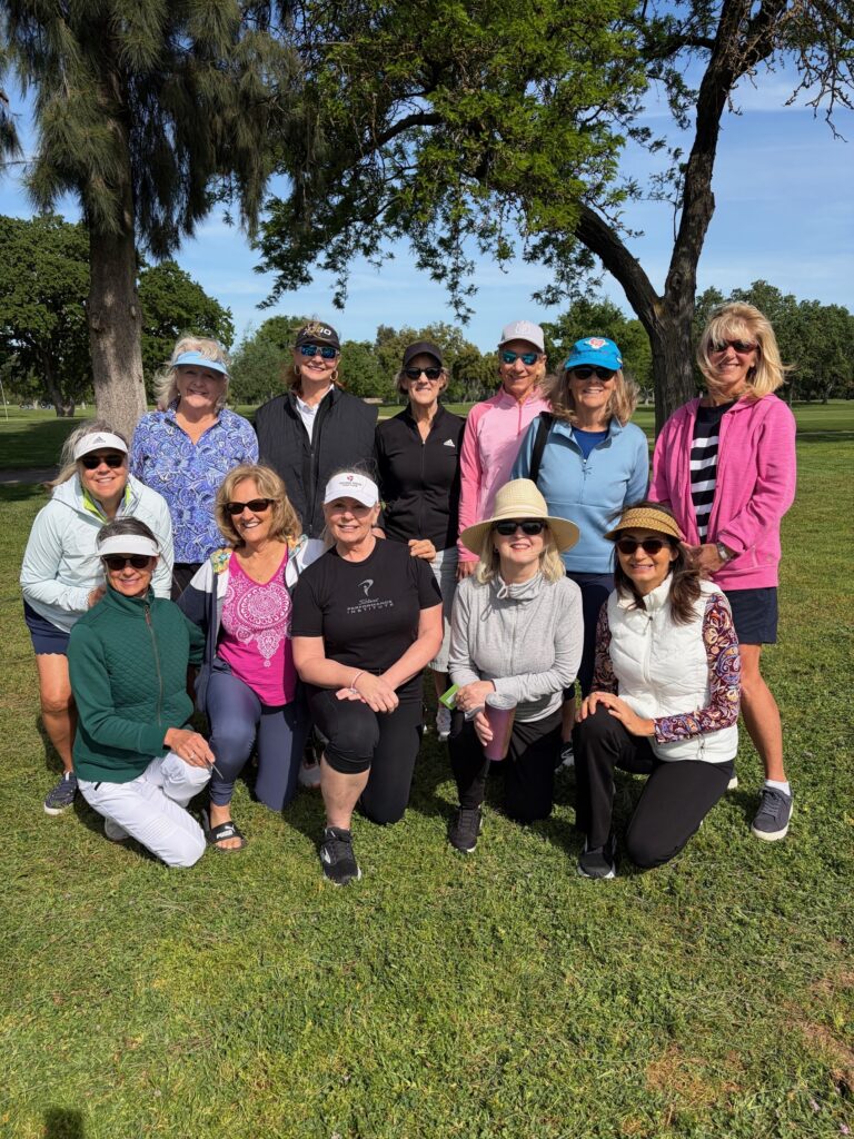 a group of women posing for a group photo on a golf course
