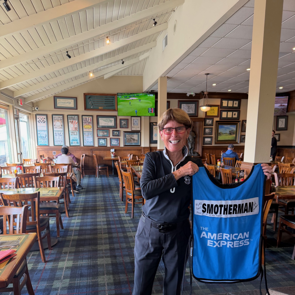 Jane from MGF holding up a sign Austin Smotherman signed caddie bib