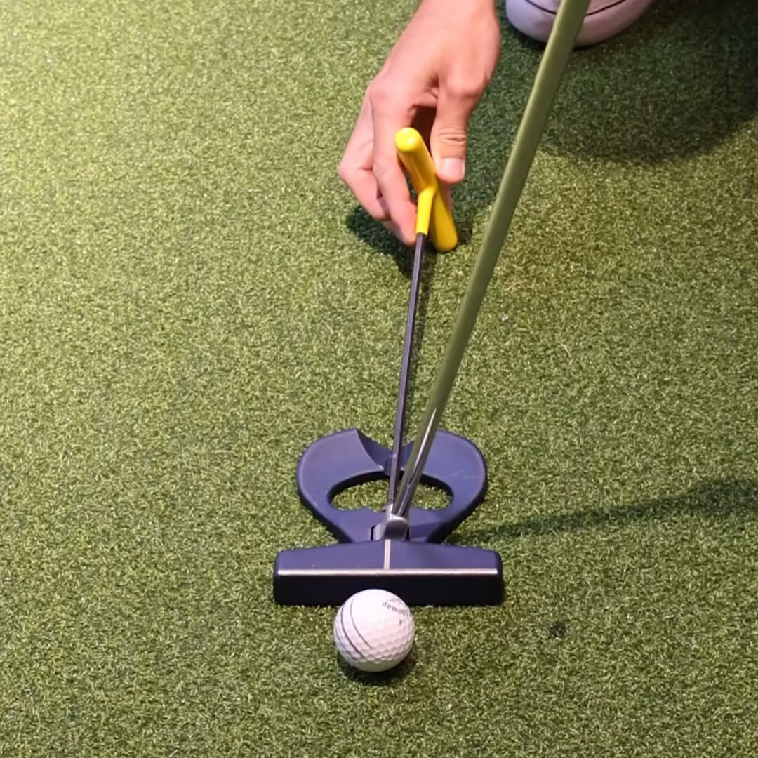 Golfer using a training aid to align a putter and golf ball on a putting green