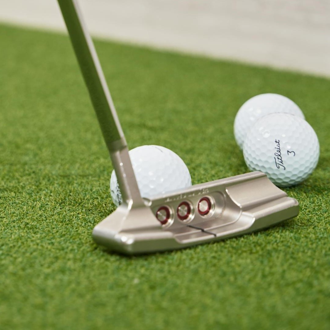 Putter and golf balls on a putting green