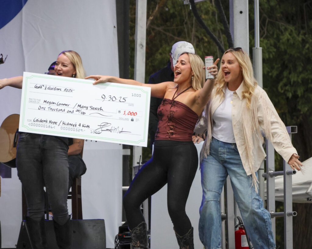 3 women excited, holding a big check.