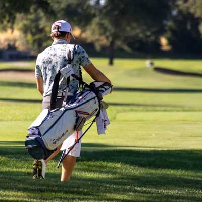 Golfer walking with a golf bag at Haggin Oaks Golf Complex in Sacramento