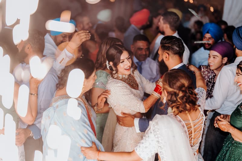 Bride celebrating on the dance floor with guests during a lively wedding reception at Haggin Oaks, surrounded by music, lights, and joyful energy.